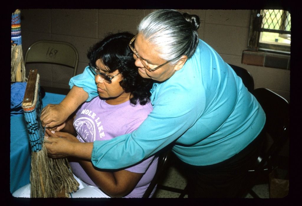 Josephine Daniels, Potawatomi yarn bag weaver, instructing an apprentice in Forest County, 1986. Photo by Rick March, WAB's first Traditional and Ethnic Arts Coordinator.